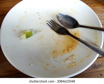 A Dirty White Plate With Stainless Spoon And Fork 