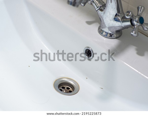 Dirty white\
sink. Open drainage. Untidy. Muddy. Stainless. Washbowl. The\
washbasin is dirty, unhygienic, has scale and rust. Bathroom\
cleaning concept. Domestic bath drain\
sink.