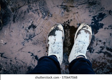 Dirty white sneaker shoes from trekking, sticking with mud, stan