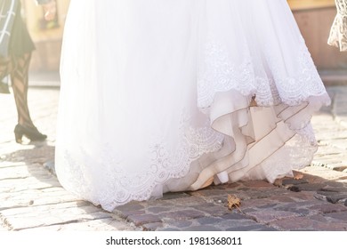 Dirty white wedding dress. Elegant bridal gown on the paving stone. The bride drags her celebrating clothing on the ground.