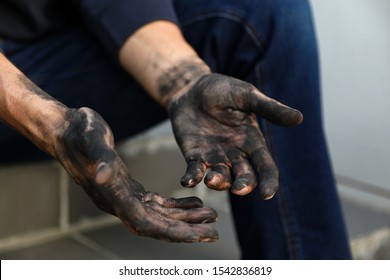 Dirty worker sitting on stairs, closeup of hands