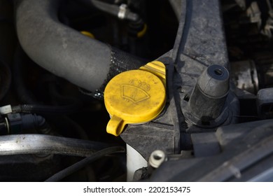 Dirty Yellow Cap Of The Windshield Wiper Fluid Reservoir Inside The Engine Compartment