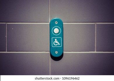 disability button on tiled wall. Modern: white button green background, grey tiles