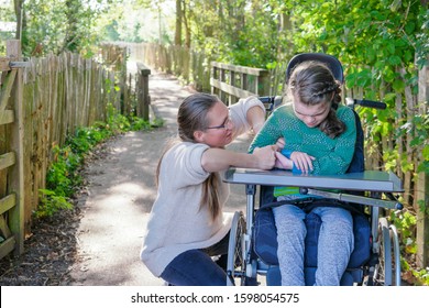 Disability, A Disabled Child In A Wheelchair Being Cared For By A Special Needs Voluntary Care Worker