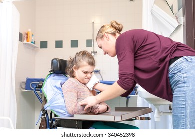 Disability A Disabled Child In A Wheelchair Having Her Face Cleaned With Help From A Voluntary Care Worker