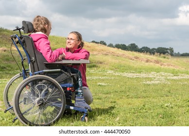 Disability A Disabled Child In A Wheelchair Relaxing Outside In The Playground With A Carer / Disability A Disabled Person In A Wheelchair