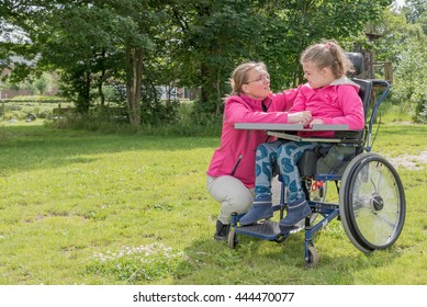 Disability A Disabled Child In A Wheelchair Relaxing Outside In The Playground With A Carer / Disability A Disabled Person In A Wheelchair