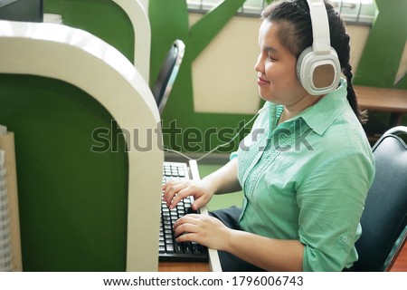 Disability young blind person happy woman in headphone typing on computer keyboard working in creative workplace office.