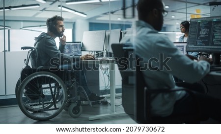 Disability-Friendly Office: Amazing IT Programmer with Disability in a Wheelchair Working on Desktop Computer. Male Specialist Create Inspirational Software. Engineer Develop Innovative App, Program
