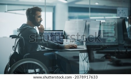 Disability-Friendly Office: Brilliant IT Programmer with Disability in a Wheelchair Working on Desktop Computer. Male Specialist Create Inspirational Software. Engineer Develop Innovative App, Program