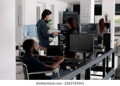 Disabled african american it engineer working on server program with computer, typing html code in coding office. web developer with chronic disability writing script with system algorithms.