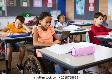 Disabled african american girl using digital tablet while sitting on wheelchair at elementary school. school and education concept