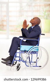 disabled african businessman sitting on wheelchair and praying