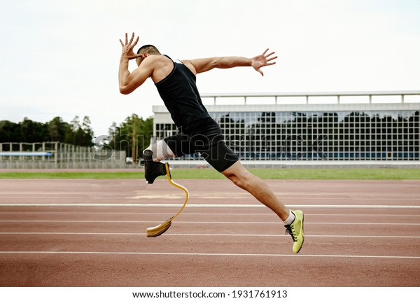 disabled athlete runner on prosthetic leg on\
track of stadium