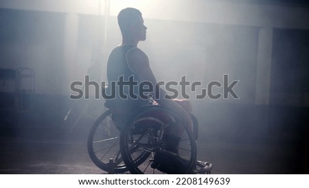 Disabled athletic man in wheelchair with dramatic hard backlight. Mobility and motivation concept