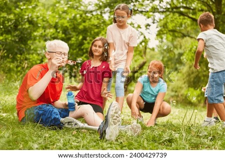Disabled boy blowing bubbles with friends while sitting at park