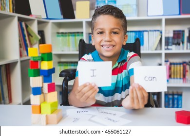 Disabled boy showing placard that reads I Can in library at school - Powered by Shutterstock