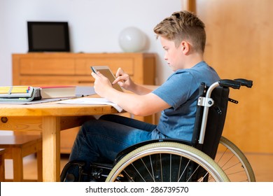 disabled boy in wheelchair doing homework and chatting in the internet