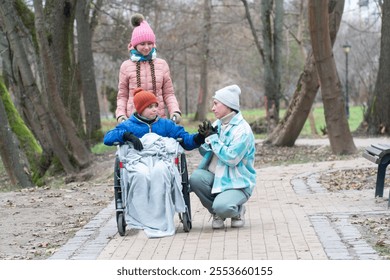 disabled boy, wheelchair, family walk in the park with a disabled child, mother with son and daughter, autumn, winter in Europe - Powered by Shutterstock