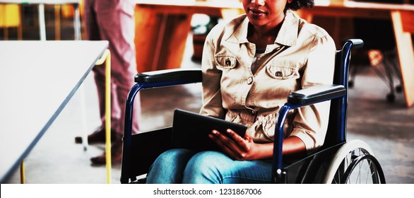 Disabled business executive in wheelchair using digital tablet in office - Powered by Shutterstock