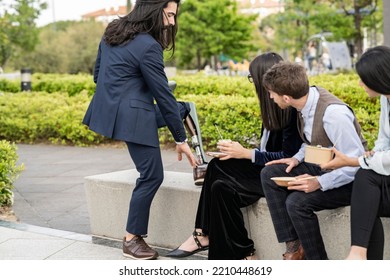 Disabled Businessman Adjusting His Prosthetic Leg Outside The Office With Co-workers.