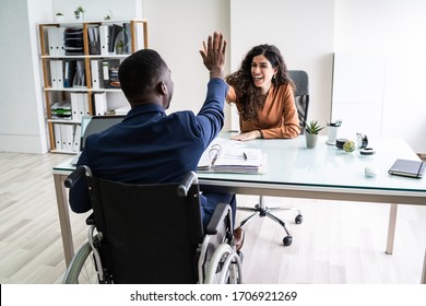 Disabled Businessman Giving High Five To His Smiling Female Partner In Office