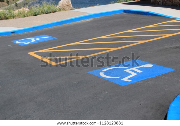 Disabled car\
park spaces as denoted by a white painted person in a wheelchair on\
a blue background and extra spacing depicted by yellow lines\
between the car park\
spaces