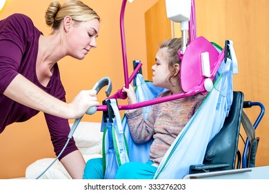 A disabled child being lifted into a wheelchair by a care assistant using special needs lifting equipment / Working with disability