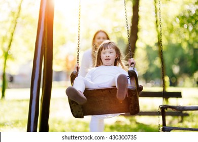 Disabled child enjoying the swing outdoors with sister