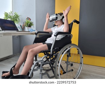 Disabled child girl using virtual reality headset with raised hands at home. Virtual reality glasses and disabled child in chair - Powered by Shutterstock