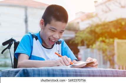 Disabled Child On Wheelchair Enjoying The Training Of Hand And Finger Muscles Through Writing With A Big Stick, Special Children's Lifestyle,Life In The Education Age, Happy Disability Kid Concept.