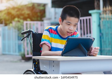 Disabled child on wheelchair happy time to use a tablet in the house with nature sun light, Special children's lifestyle, Life in the education age of special need kid, Happy disability boy concept.