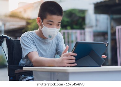 Disabled child on wheelchair happy time to use a tablet in the house with nature sun light, Special children's lifestyle, Life in the education age of special need kid, Happy disability boy concept.