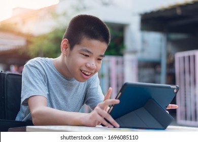 Disabled Child On Wheelchair Happy Time To Use A Tablet In The House With Nature Sun Light, Special Children's Lifestyle, Life In The Education Age Of Special Need Kid, Happy Disability Boy Concept.