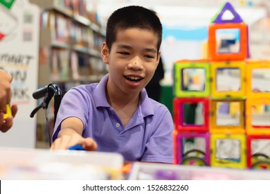 Disabled Child On Wheelchair Is Interested In Skills Development Toys In Books And Toys Fair,Special Children's Lifestyle,Life In The Education Age Of Special Need Kids,Happy Disability Kid Concept.