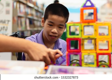 Disabled child on wheelchair is interested in skills development toys in Books and toys fair,Special children's lifestyle,Life in the education age of special need kids,Happy disability kid concept.