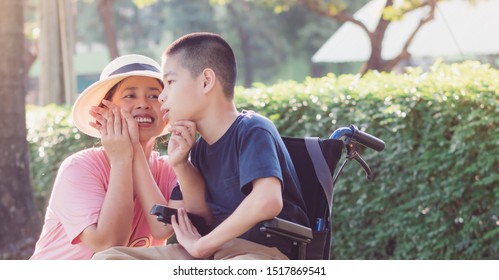 Disabled child on wheelchair and mom in the outdoor park, His mother sent love through the eyes and gentle hands touch, Life in the education age of special children, Happy disability kid concept.