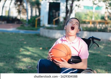 Disabled Child On Wheelchair Is Playing Basketball On The Lawn In Front Of The House Like Other People, Lifestyle Of Special Child,Life In The Education Age Of Children, Happy Disability Kid Concept.