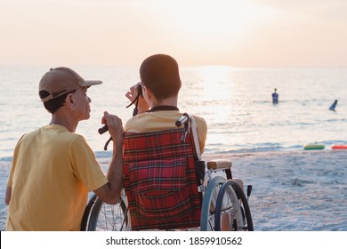 Disabled child on wheelchair is smiling,take photo camera with parent on the sea beach like other people,Lifestyle of special child, Life in the education age of children,Happy disability kid concept.