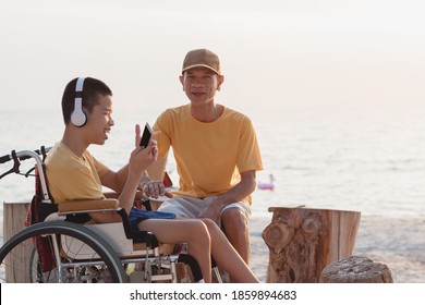 Disabled child on wheelchair is smiling,use smartphone with parent on the sea beach like other people,Lifestyle of special child, Life in the education age of children, Happy disability kid concept.