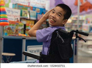 Disabled Child On Wheelchair Trying Begged Parents To Buy A Toy For Him In Books And Toys Fair,Special Children's Lifestyle,Life In The Education Age Of Special Need Kids,Happy Disability Kid Concept.