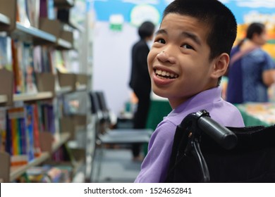 Disabled Child On Wheelchair Trying Begged Parents To Buy A Book For Him In Books And Toys Fair,Special Children Lifestyle,Life In The Education Age Of Special Need Kids,Happy Disability Kid Concept.