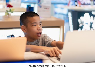 Disabled Child On Wheelchair Trying To Use A Computer With Excitement In An IT Shop , Special Children's Lifestyle, Life In The Education Age Of Special Need Kids, Happy Disability Kid Concept.