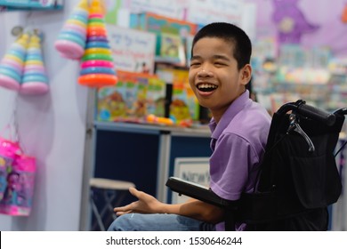 Disabled Child On Wheelchair Trying Begged Parents To Buy A Toy For Him In Books And Toys Fair,Special Children's Lifestyle,Life In The Education Age Of Special Need Kids,Happy Disability Kid Concept.