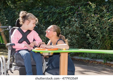 A Disabled Child In A Wheelchair Being Cared For By A Special Needs Carer / Working With Disability