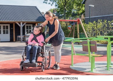 A Disabled Child In A Wheelchair Being Cared For By A Special Needs Carer / Working With Disability