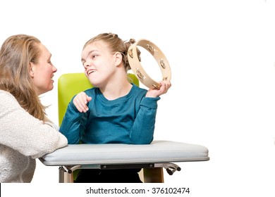 Disabled Child In A Wheelchair Having Music Therapy Together With A Special Needs Carer / Working With Mentally Handicapped Children