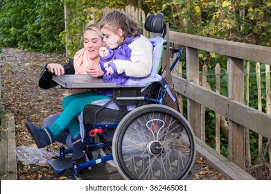 Disabled Child In A Wheelchair Relaxing Outside With A Carer / Working With Disability