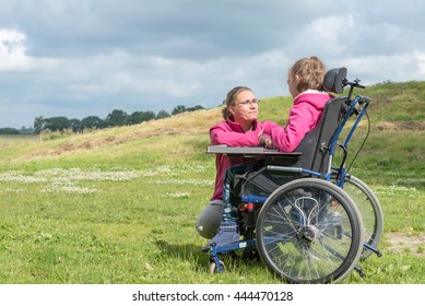 Disabled child in a wheelchair relaxing outside in with a special needs carer / Working together with disability