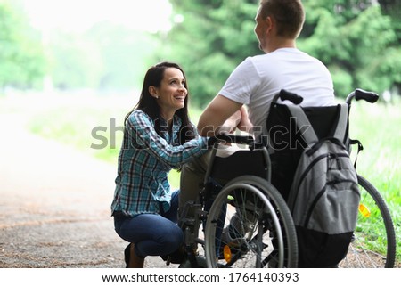 Disabled couple in love on a walk in park portrait. Wife looks at her husband in love with eyes. Rehabilitation disabled person after car accident concept